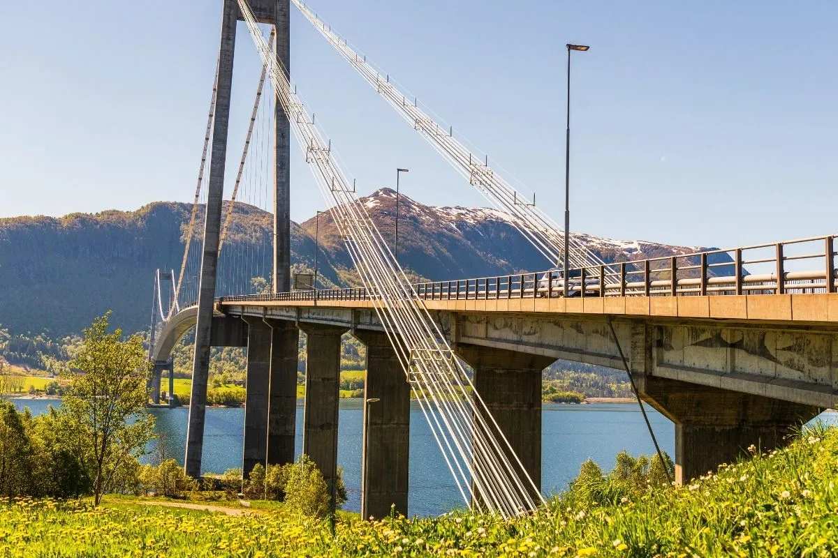 Een hangbrug die een weg over een fjord draagt, met bergen erachter