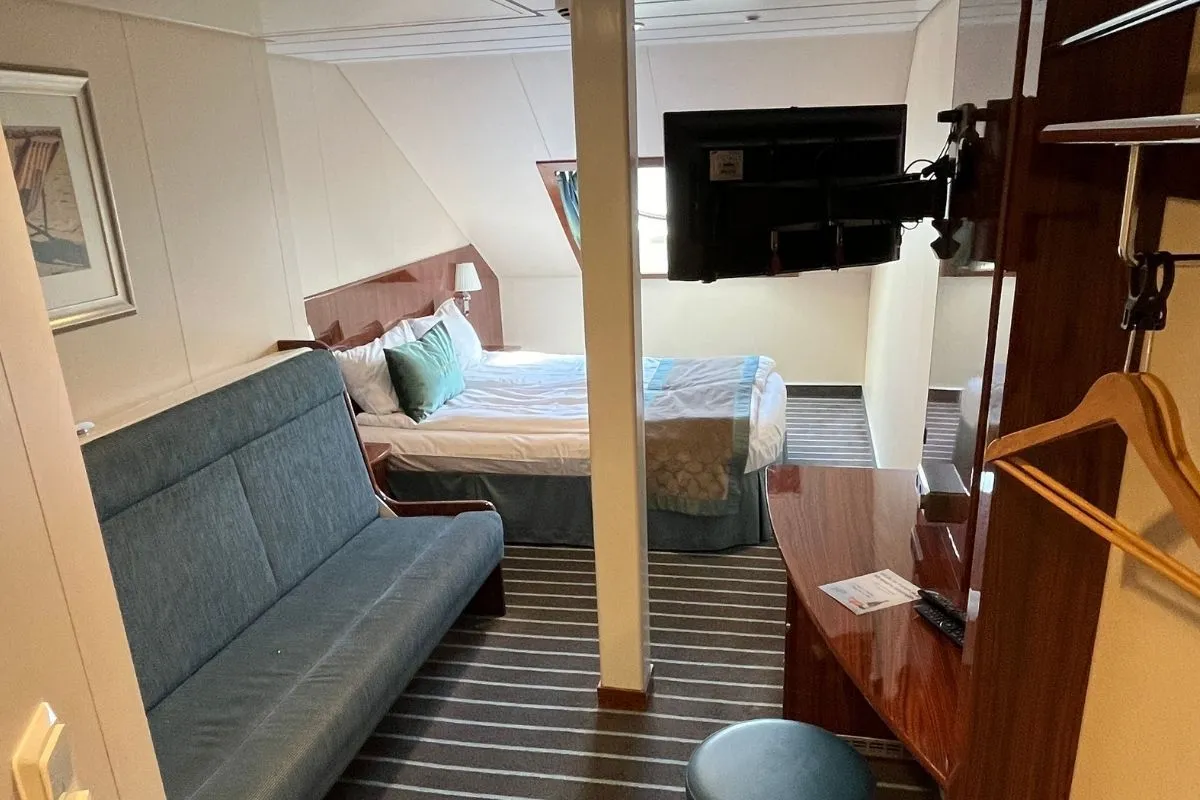 Een hut op een Fjord Line-veerboot met een tweepersoonsbed, een slaapbank, een bureau en een tv