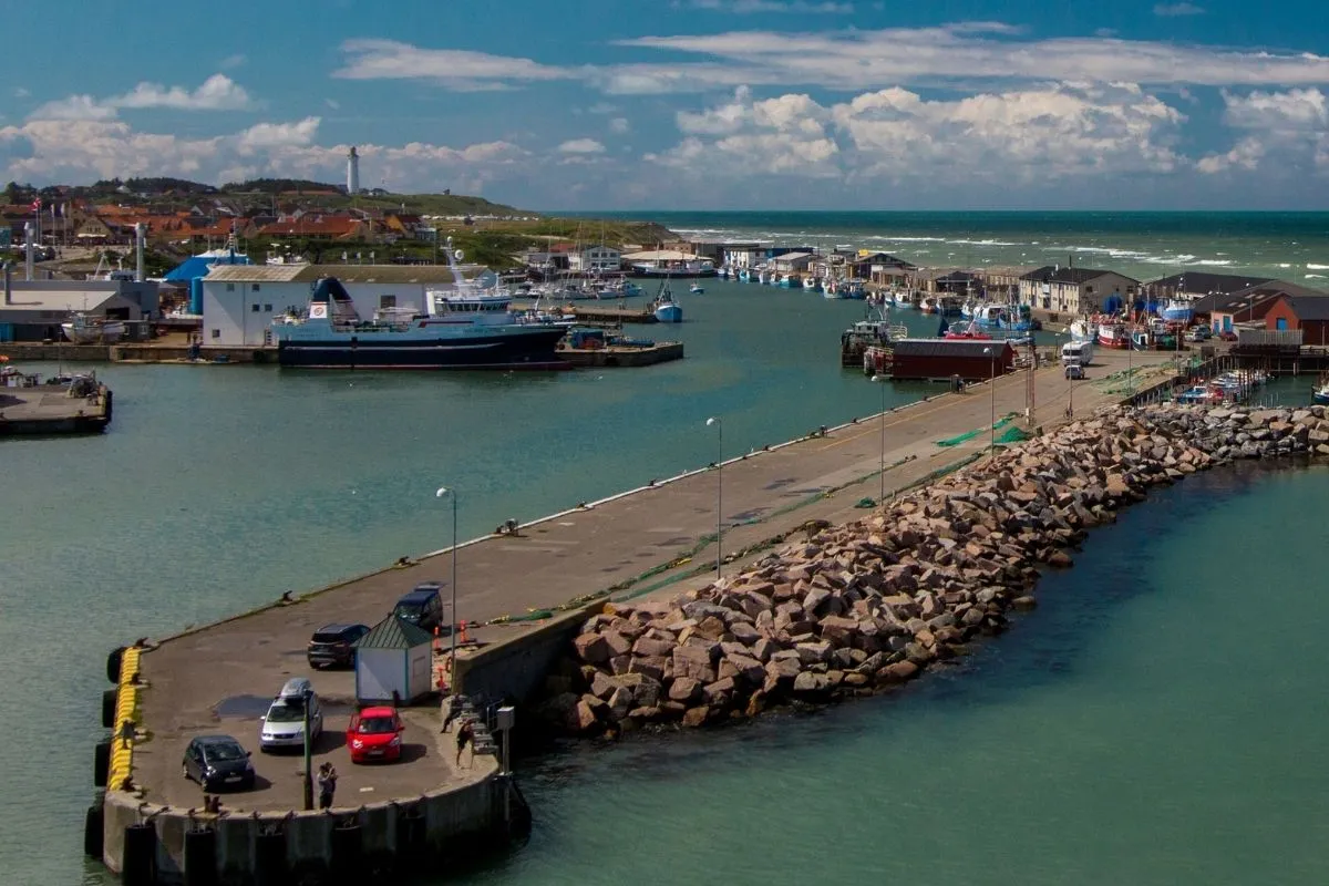 De haven van Hirtshals met de golfbreker, vissersboten en auto's op de kade